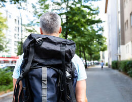 A man wears a hiking pack on an urban street.